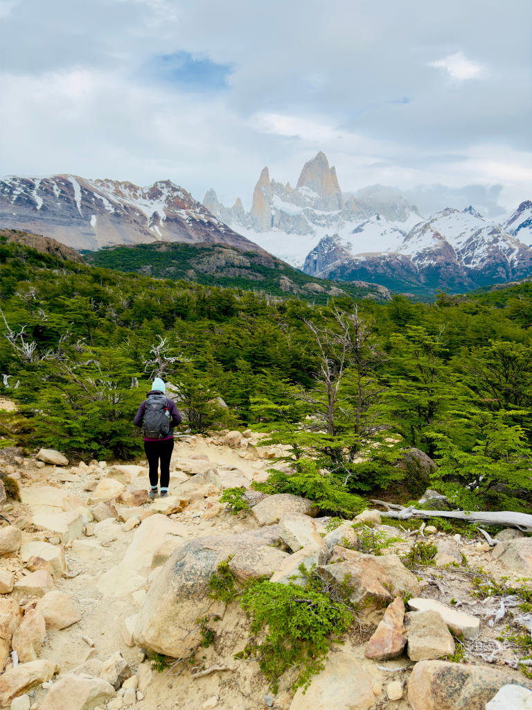 Hiker on trail in Patagonia Argentina with Mount Fitz Roy and snow capped peaks in background