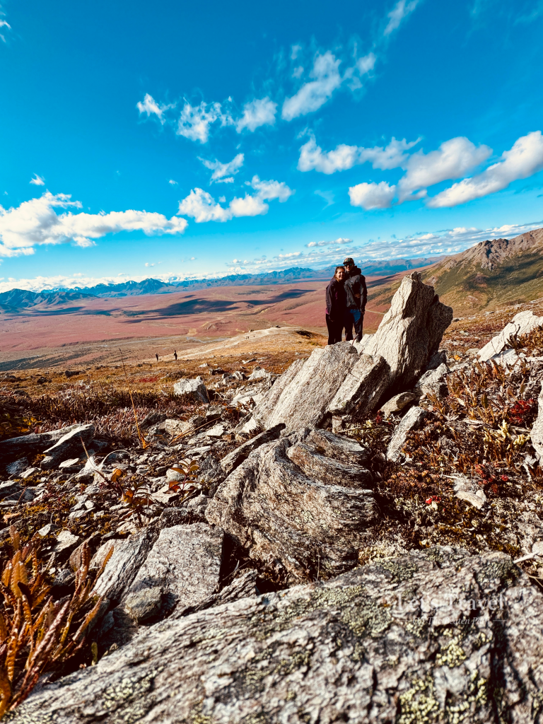 Couple hiking in Denali National Park Alaska overlooking tundra landscape and mountain range