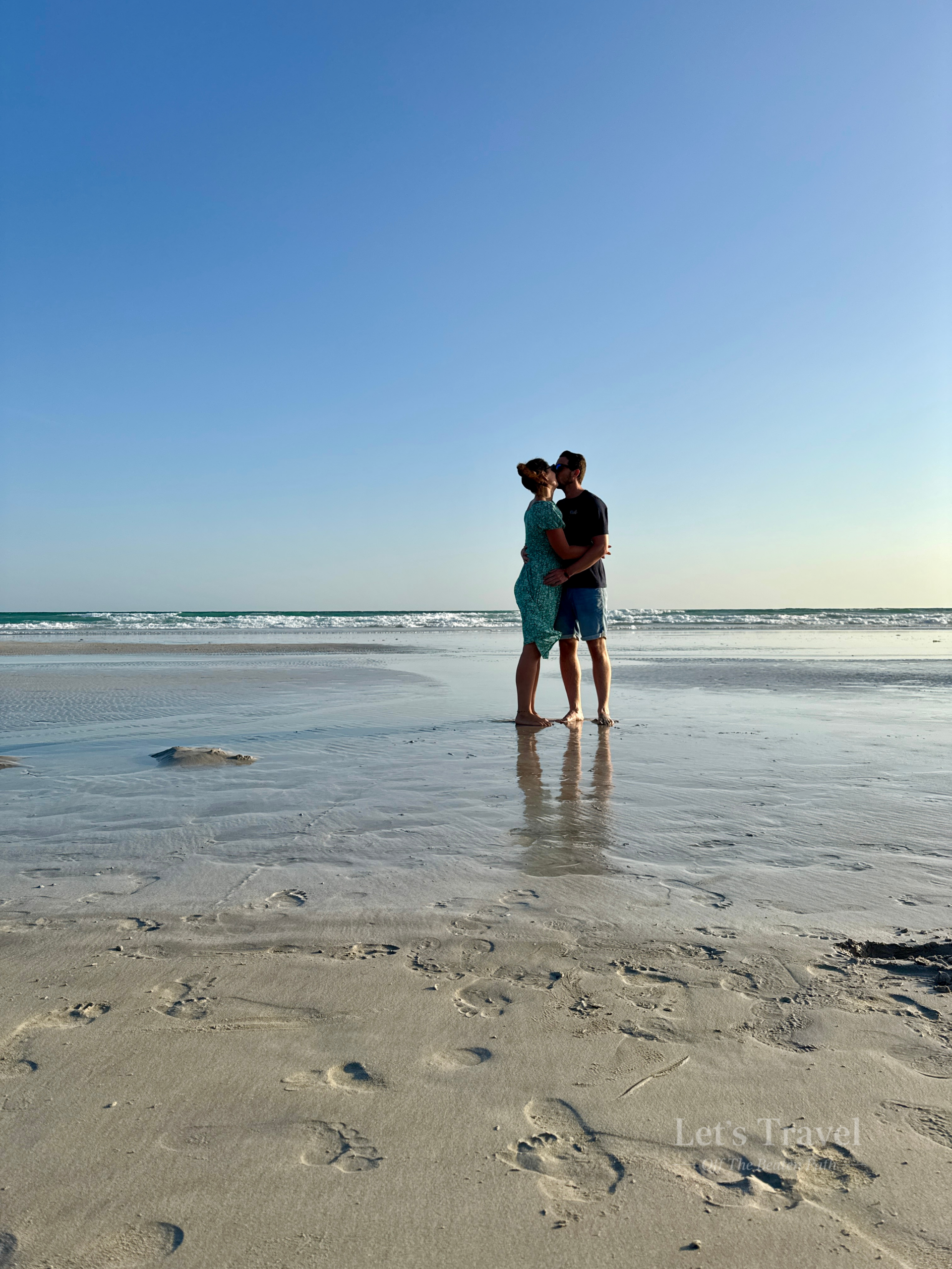 Couple standing on beach in Salalah Oman with ocean waves and sandy shoreline