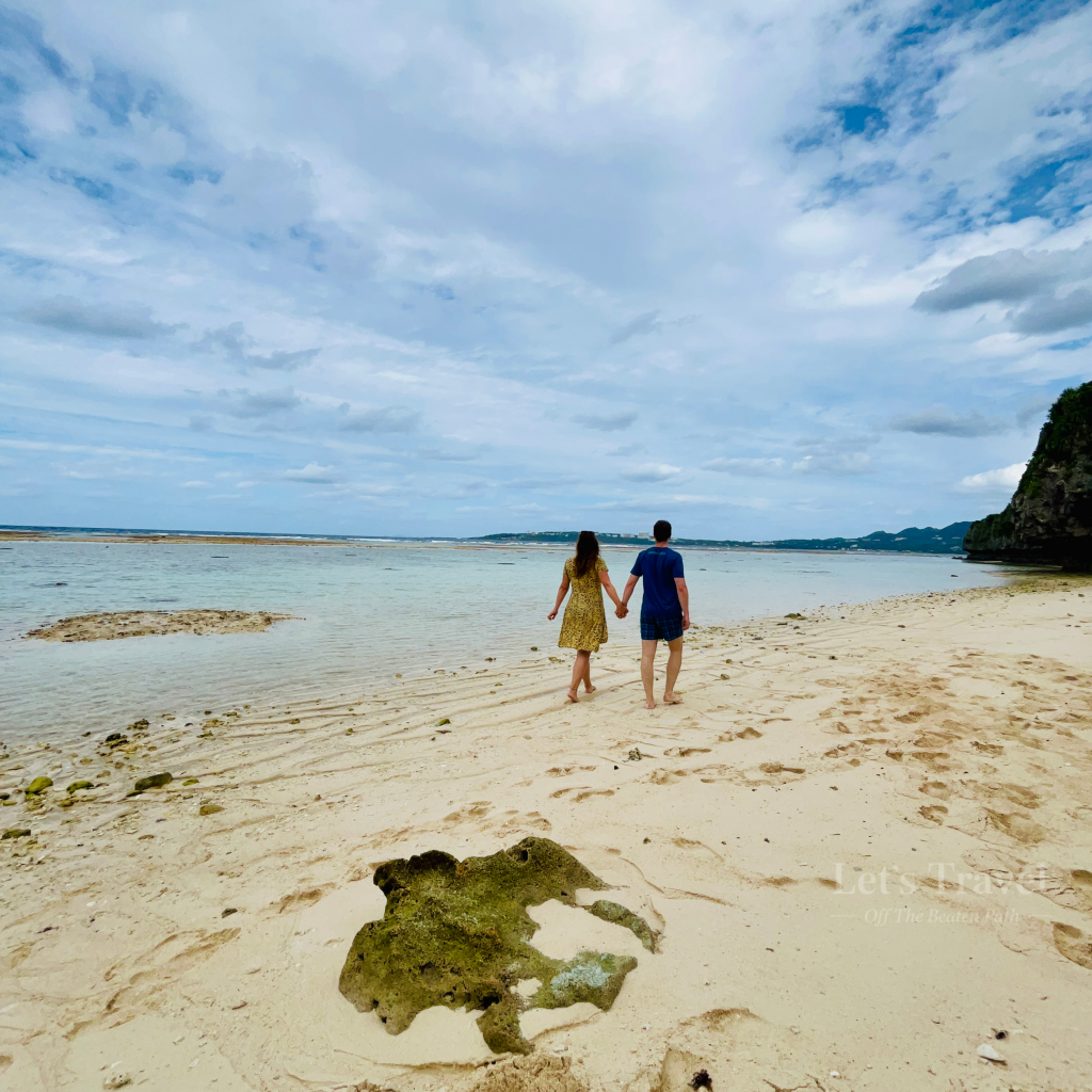 Couple walking on sandy beach in Okinawa Japan with clear water and tropical coastline