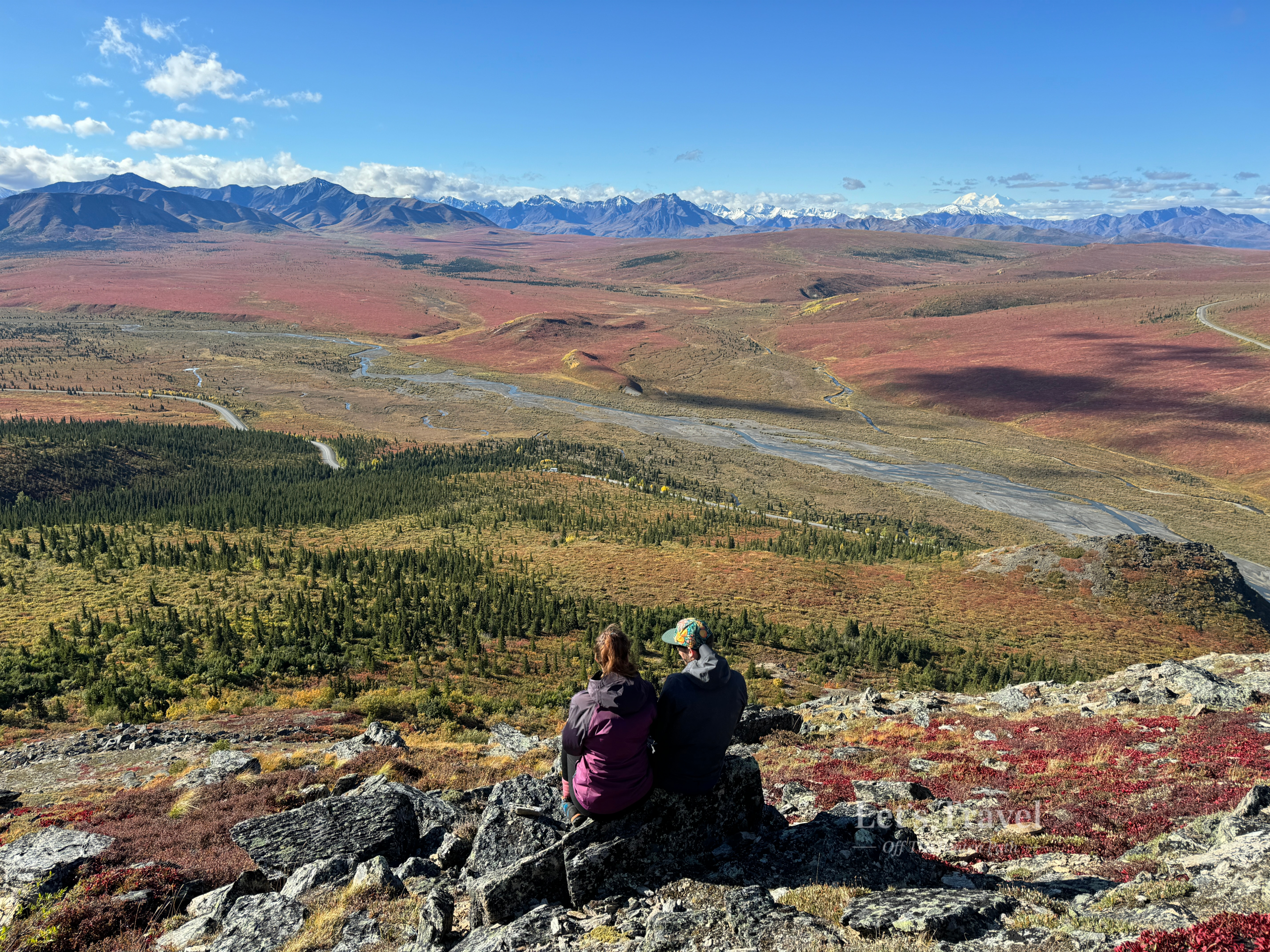 Couple overlooking vast tundra landscape in Denali National Park Alaska with mountains and river valley
