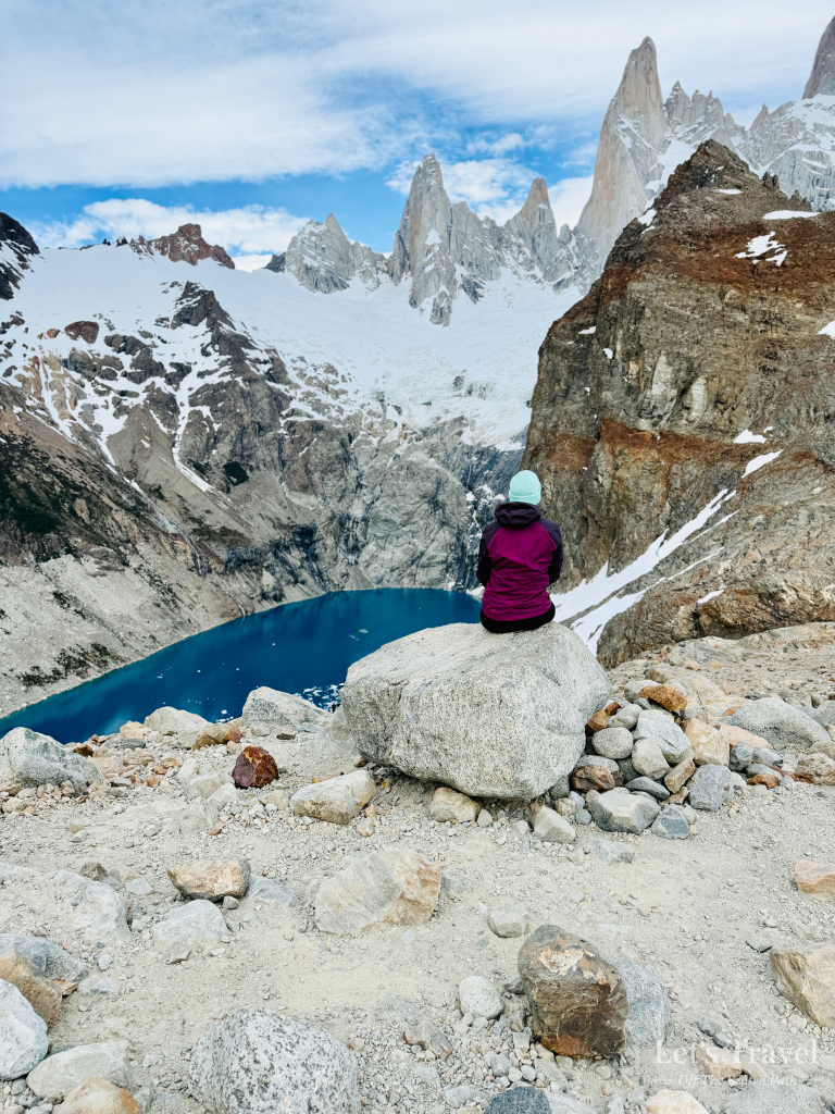 Solo hiker sitting on a rock overlooking Laguna de los Tres and Mount Fitz Roy in Los Glaciares National Park, Patagonia, Argentina.