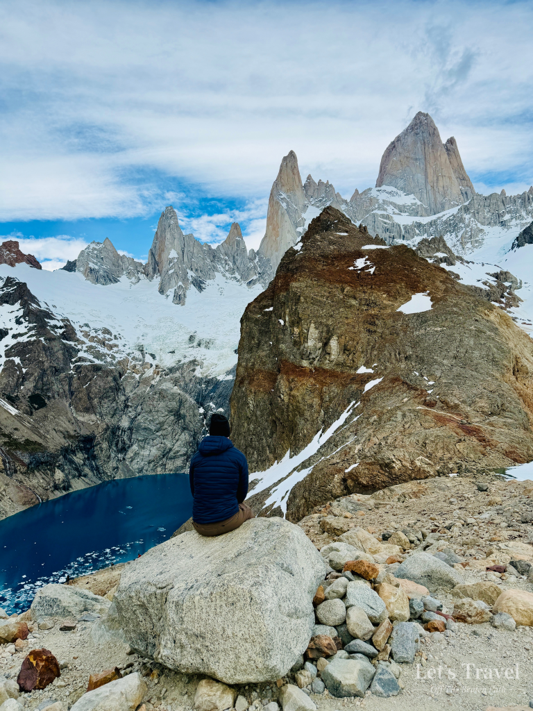Solo hiker sitting above Laguna de los Tres with Mount Fitz Roy in Los Glaciares National Park near El Chaltén, Patagonia, Argentina.