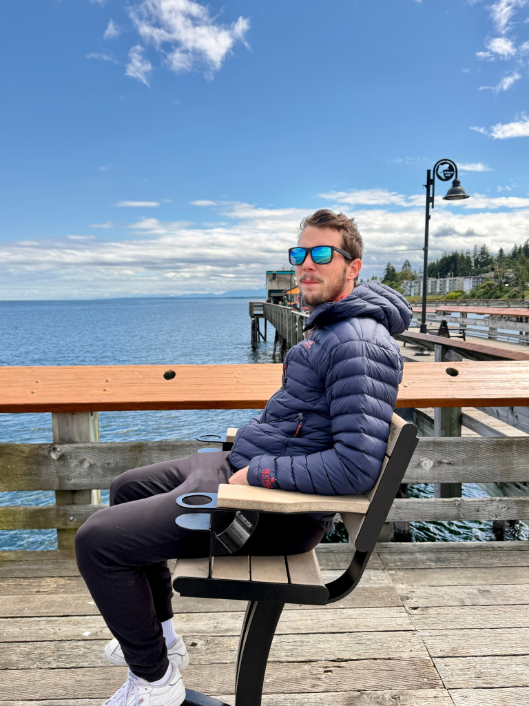 Man relaxing on a wooden pier at Campbell River waterfront on Vancouver Island, British Columbia, overlooking the ocean.